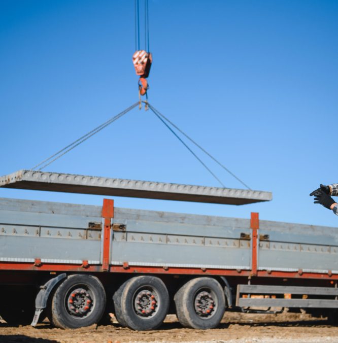The builder controls the unloading of the panels for the roof of the house with a crane.